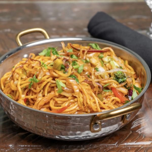 Himalayan Doko's vegetable chowmein noodles with broccoli, peppers, and onions in a hammered metal bowl.