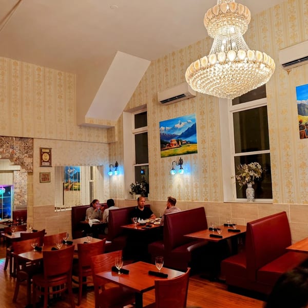 Himalayan Doko restaurant interior with patrons dining at tables and booths under a large chandelier.