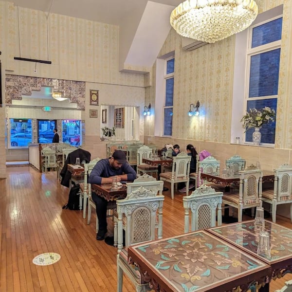 Himalayan Doko's spacious dining room with ornate wooden tables and chairs, patterned wallpaper, and a large chandelier.