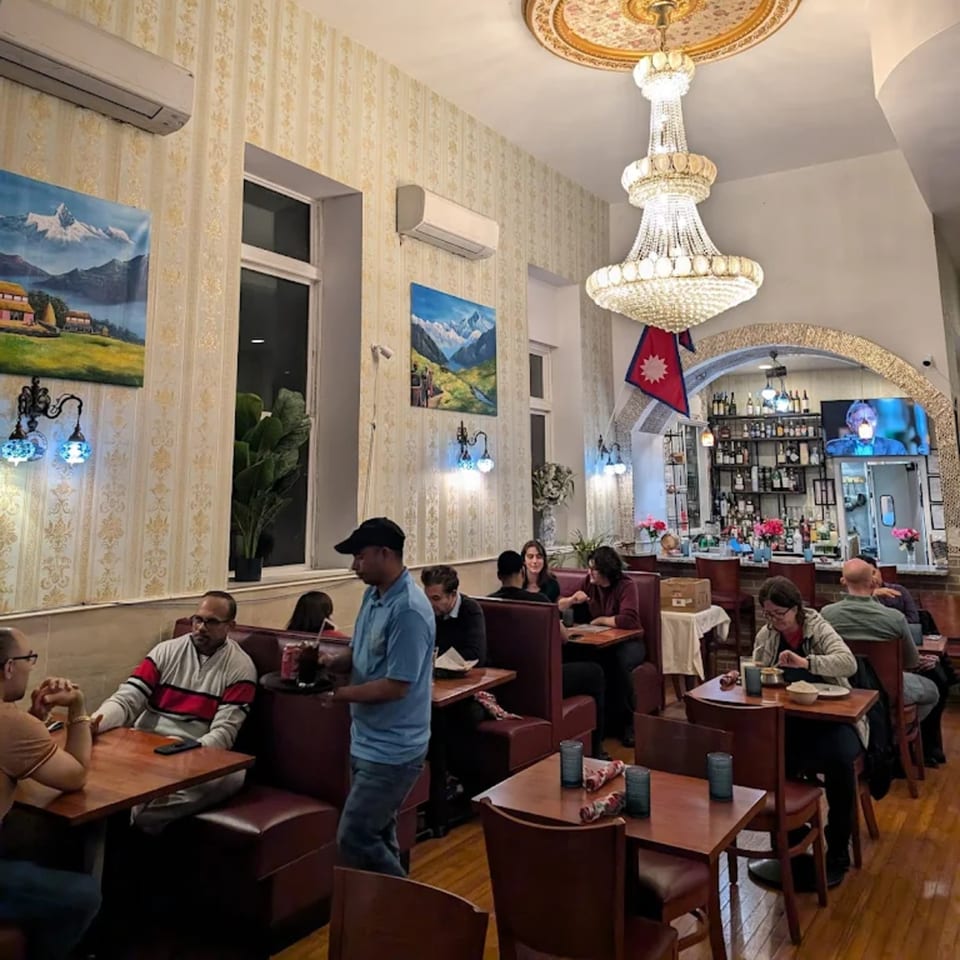 Diners seated at tables and booths in the Himalayan Doko restaurant, with a bar in the background.