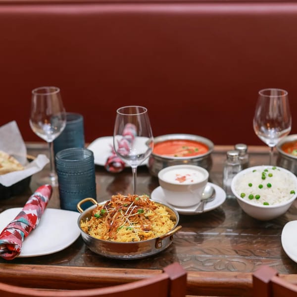 An Indian feast with biryani, rice, curry, and raita on a wooden table at Himalayan Doko.